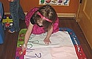 Charlotte is writing letters on the AquaDoodle mat