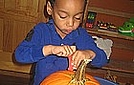 Corin is cutting the top off the pumpkin